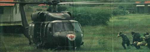 Army MEDIC with M-5 aid bag on back supervises loading of his patient onto the helicopter